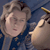 Pixelated image of a person with light brown hair holding a golden object near their face against a dark blue background.