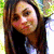 Pixelated close-up of a person with long brown hair wearing dark clothing against a blurred green and white background.