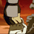 Pixelated character with dark hair and light skin holds a white object against a red-orange background, with a small black-and-white number in the corner.