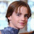 Pixelated close-up of a person with brown hair wearing a blue top against light background.