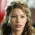 Pixelated close-up of a person with light brown curly hair, wearing dark clothing against a red and gray background.