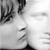 Black-and-white pixelated icon showing partial face with visible eye, nose, and mouth features in grayscale tones.
