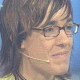 A person with brown hair and glasses wears a yellow shirt, headset microphone, and dark necklace across three views showing facial expression changes.