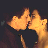 Static pixelated icon of two yellow-orange figures in a kissing pose against dark background with visible dithering and color blending.