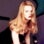 Pixelated image of a person with long light brown hair wearing dark clothing against a gradient background.