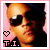 A pixelated portrait of a person wearing dark sunglasses and a black top against a pink background, with 'T.I.' text and heart symbol in the corner.