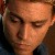 Pixelated close-up of a person's face with closed eyes, light skin tone, and dark hair visible at the edges, set against a dark background.