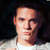 Static pixelated image of a person's face and upper shoulders against dark background with light-colored clothing.