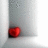 A static pixelated image shows a red heart-shaped object resting on a gray surface with subtle shading.