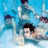 Four people in swimwear pose underwater with arms raised, feet visible, against a blue background.