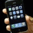 A hand holds a black smartphone with app icons on screen, surrounded by red pixelated text reading 'hands off', 'tths my iphone', and 'bitch'.