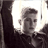 Static 48x48 pixel icon showing a person's face in grayscale with high contrast, partially obscured by dark vertical elements on both sides against a bright background.
