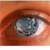 A close-up of a human eye with a brown iris and visible eyelashes, rendered in pixelated style with orange-brown skin tones surrounding the eye.