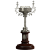 A pixelated trophy with a dark brown base, metallic stem, and silver bowl, set against a plain light gray background.