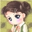 Pixelated anime-style character with brown hair, large dark eyes, and pink cheeks, wearing a white-collared shirt with green stripes and a brown tie against a muted green background.