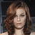 A woman with wavy brown hair and blue eyes appears in three showing slight head movement against a dark background