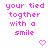 Pixelated pink text reads 'your tied together with a smile' across four lines on white background, two heart symbols below.