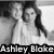 Two grayscale figures in formal attire stand side-by-side with a blurred background; text at the bottom reads "Ashley Blake" in pixelated font.