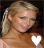 A pixelated image of a person with blonde hair tied back, wearing a light-colored top and holding a white heart shape in the left hand.