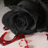 A black rose with red blood-like stains on a light background, accompanied by pixelated red text about broken hearts.