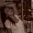 Pixelated grayscale image of a figure with dark hair and light clothing, standing in front of an indistinct background.