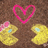 Two yellow duck-shaped objects with blue eyes and pink bows face each other on a brown background, with a pink heart above them and red text reading "Luv is in the air!".