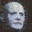 Pixelated grayscale image of a human skull with hollow eye sockets and nasal cavity, set against dark background.