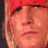 Static pixelated image of a person's face with red headwear, light skin tone, and visible eyes nose mouth against dark background.