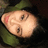 Pixelated close-up of a light-skinned face with closed eyes, pink cheeks, and dark hair against a green background.