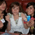 A group of people in a theater setting, with one person holding a blue cup and another wearing a white shirt.