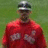 Pixelated image of a person in red sports uniform with number 33, standing against green background, next to text identifying name and team.