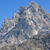 A pixelated mountain peak with layered gray and white tones against a solid blue background, showing no visible text or distinct objects.
