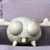 Pixelated static image of a rounded white creature with closed eyes, two small legs, and wing-like appendages against a gradient background.