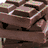Stacked chocolate bars with visible lines and a brown wrapper, set against a light background