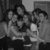 Black-and-white pixelated image of multiple figures in a group pose with indistinct facial features and clothing details.