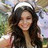 A pixelated static image shows a person with long dark hair wearing headphones and a light-colored top against an outdoor background.