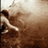Pixelated static image shows a figure in motion against a gradient background with no visible text or distinct objects.