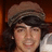 Pixelated image of a person with dark hair and a brown cap, split into four quadrants with pink text on black backgrounds.