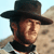 Static pixelated image of a man in profile wearing a dark wide-brimmed hat with light brown skin tone and beard, set against a pale blue sky background.