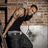 A pixelated image shows a man in a black tank top leaning against a brick wall with text overlays reading "Gimme That" and "Kiss Kiss Wall to Wall."