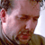 Pixelated close-up of a person's face with visible facial features and partial clothing, rendered in low-resolution static GIF format.