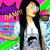 Pixelated image of a person with long black hair wearing white top, holding purple cat-shaped object against pink and green background.
