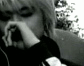 Black-and-white animation of a person with light hair covering their face with one hand, showing slight variations in hand position and background blur across frames.