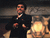 Static pixelated image of a man in formal attire standing near a fireplace with visible flames, rendered as a low-resolution buddy icon.