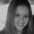 Black-and-white pixelated image of a person with long straight hair, smiling with eyes partially closed, against a light background.