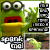 Green puppet with large eyes and glasses, red mouth, yellow lower face, raised hand, text "I'M A BAD, BAD TOAD! I NEED A SPANKING!" and "spank me!" on screen.