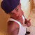 A person wearing a dark blue beanie and white tank top, with a light brown background, shown in a sequence of with slight pose changes