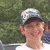 A pixelated image of a person wearing a cap and white shirt, with green and gray background containing text