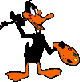 Daffy Duck character in black suit with orange beak, feet, and prop, holding a small black hat and orange object with green details against gray background.