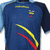 Blue athletic shirt with yellow and red diagonal stripes, small emblem on chest, light blue shoulder accents.